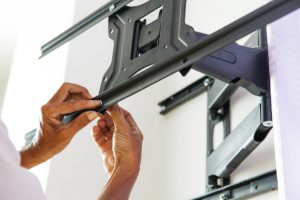 Hands installing a grey steel tv mount